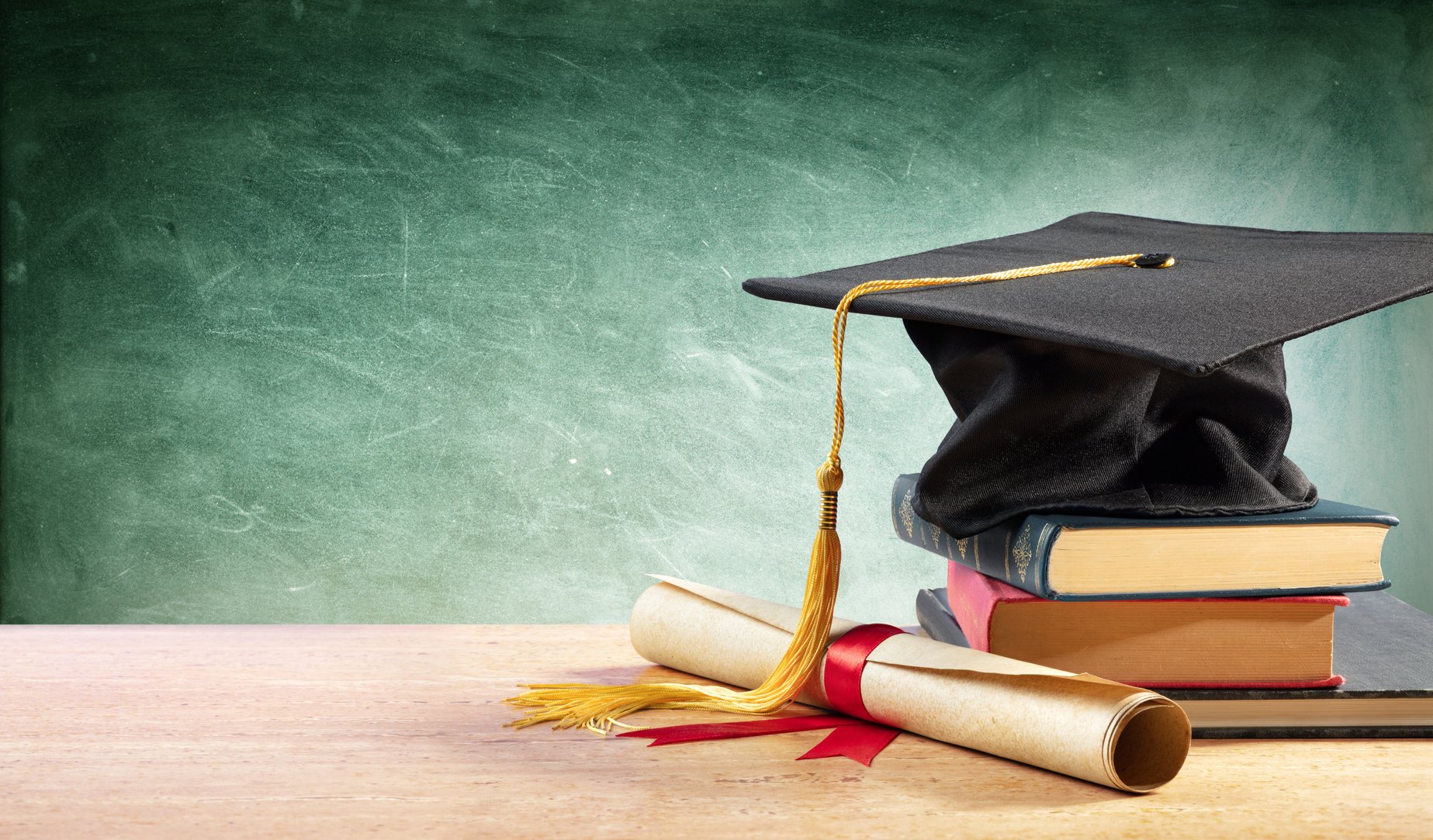 Graduation Cap And Diploma On Table With Books